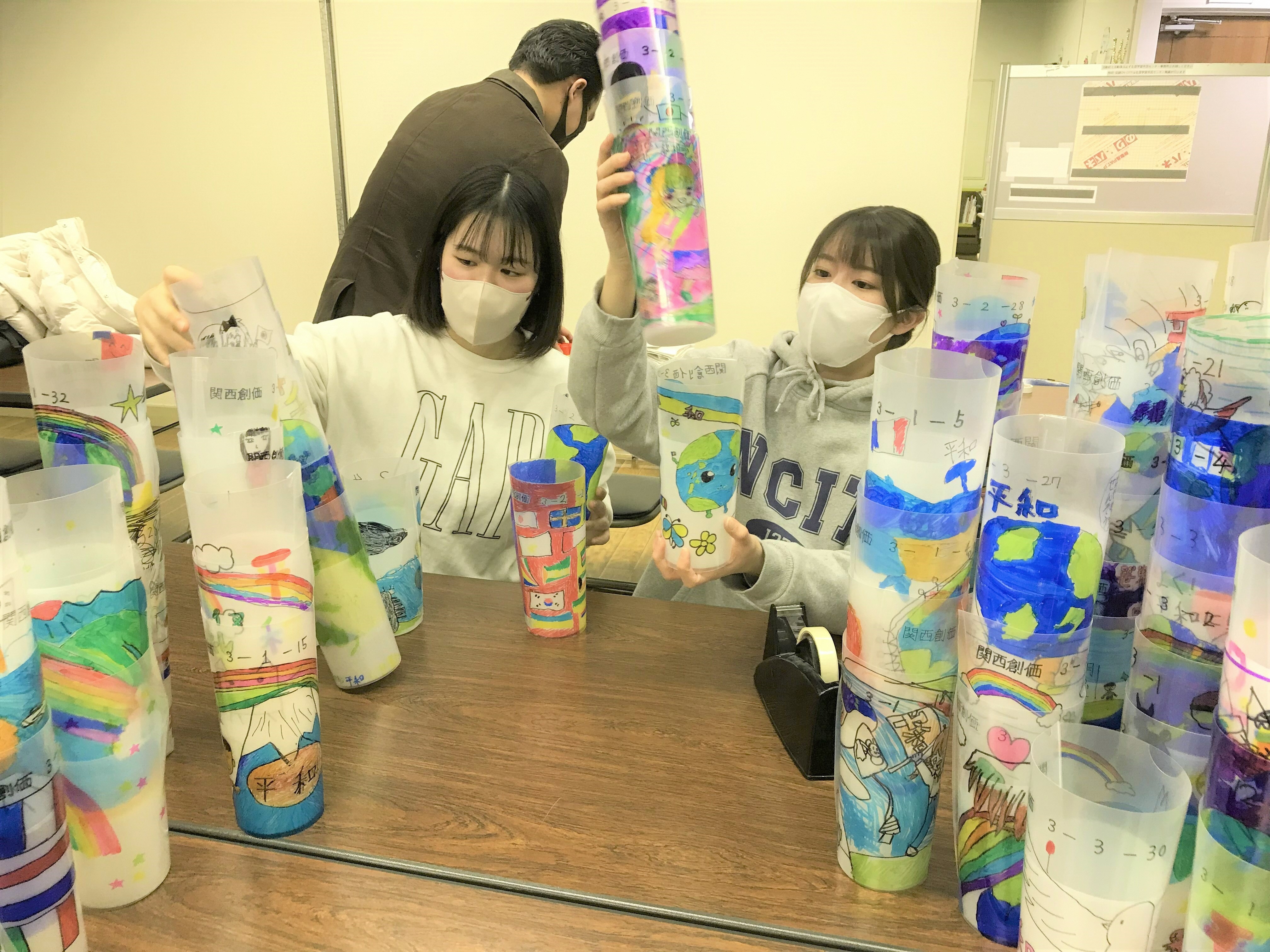 平和メッセージをカップ巻き付ける大学生