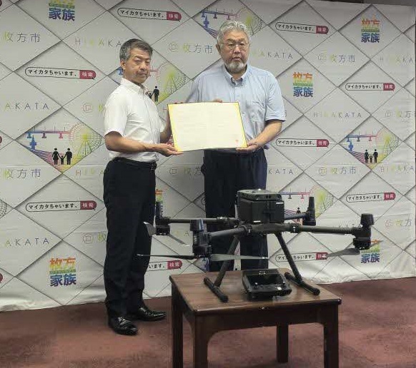 協定書を持っている伏見市長（写真左）、DiO代表取締役 一筆様(写真右) 