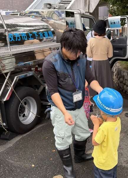 給水活動のそばで子供がヘルメットをつけている様子